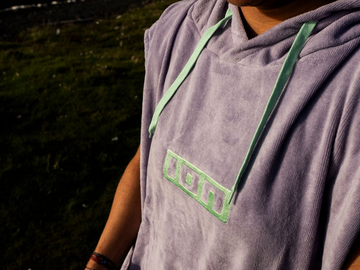 ION Poncho Core 2026 grau mit grünem Logo, Kapuze und Kordelzug, Detailansicht Vorderseite