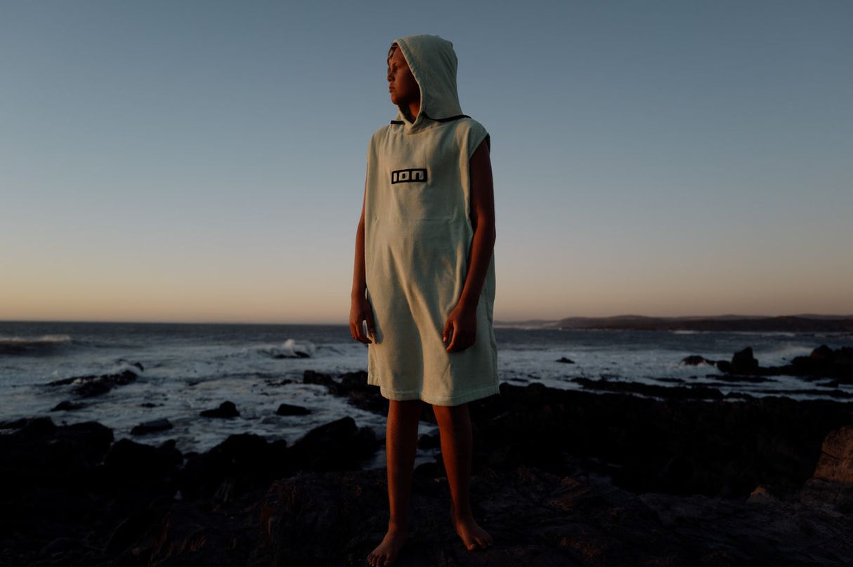 ION Grom 2025 Poncho in Beige mit Kapuze, Person am Strand stehend, Frontalansicht