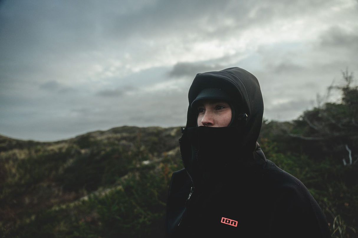 ION Neo Cosy Coat 2026 schwarz, Frontansicht, Person mit Kapuze in Landschaft