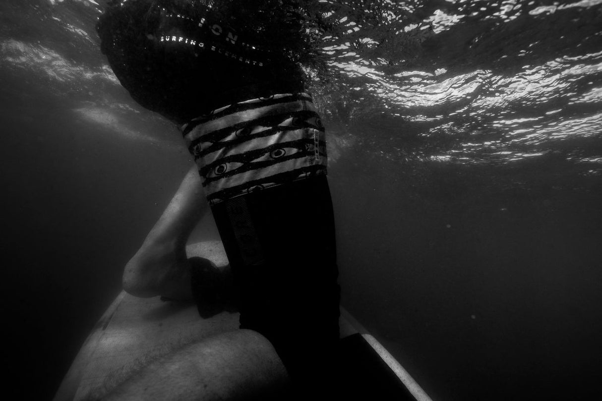ION Wing Knee Sleeve 2026 schwarz mit Riemen, Unterwasser-Seitenansicht am Bein getragen
