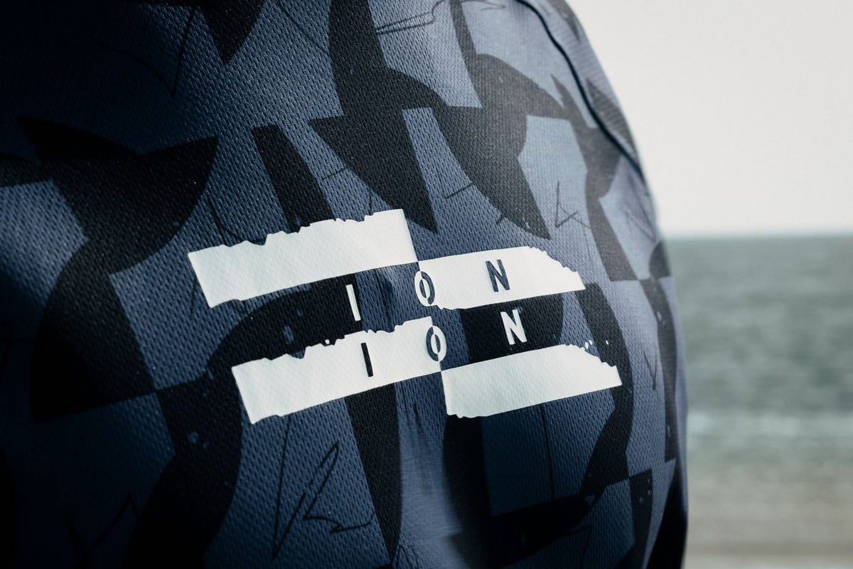 ION Wetshirt Hood Langarm Herren 2026 navy Karo-Muster mit ION-Logo, Frontalansicht am Strand
