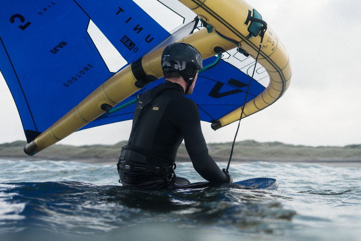 ION Slash Amp 2026 Kiteboard blau-gelb mit Sportler im Wasser, Frontalansicht