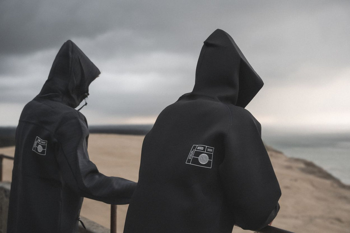 ION Neo Hoody Reversible 2026 in Schwarz, Neopren-Kapuzenpullover, Rückansicht von zwei Personen am Strand