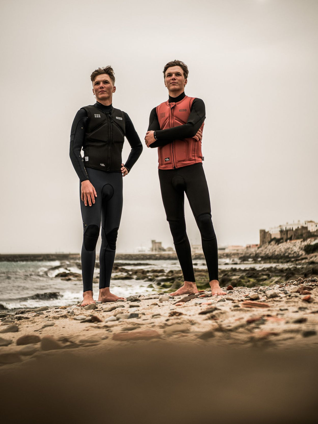 ION Collision Vest Core Front Zip 2026 in Rot und Schwarz, Frontalansicht an zwei Trägern am Strand getragen