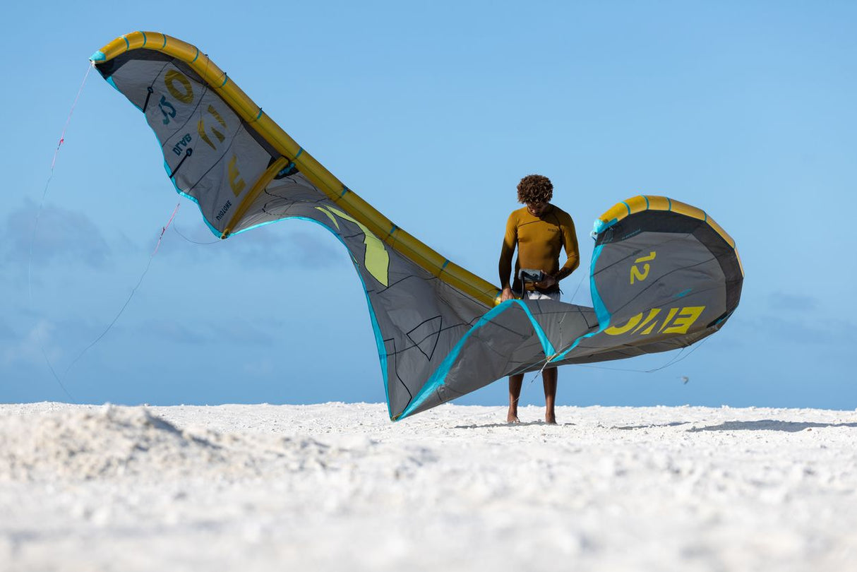 ION Neo Top 0.5 LS Herren Langarm-Neoprenshirt in Gelb und Grau, Frontansicht am Strand mit Kiter und Kite