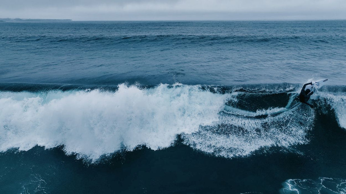 ION Seek Amp 6/5 Neoprenanzug mit Kapuze in Blau, Frontalansicht im Wasser beim Surfen