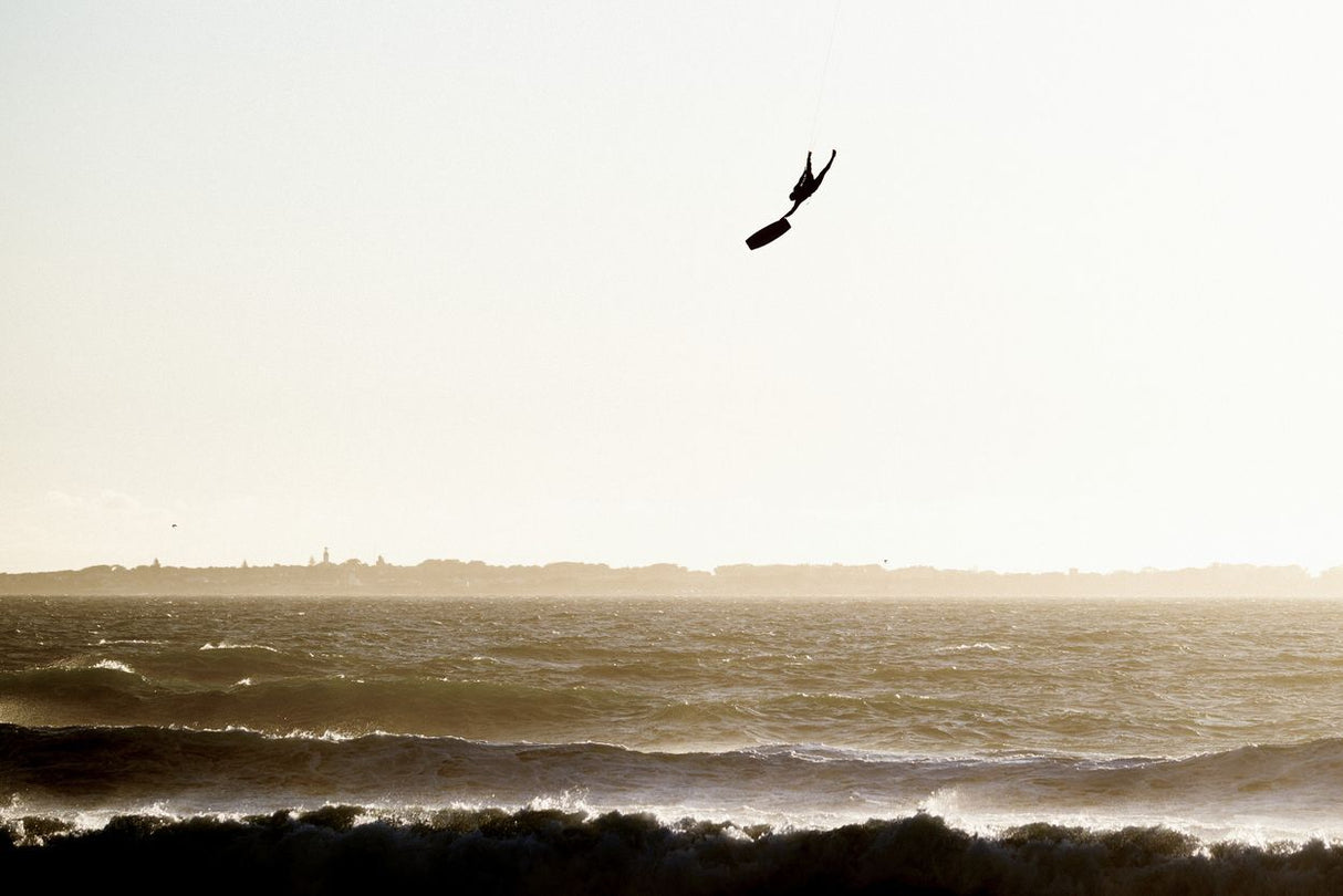 ION Nova Kite Trapez Damen 2024 in Schwarz, Kitesurfer in Aktion über Wellen, Frontalansicht
