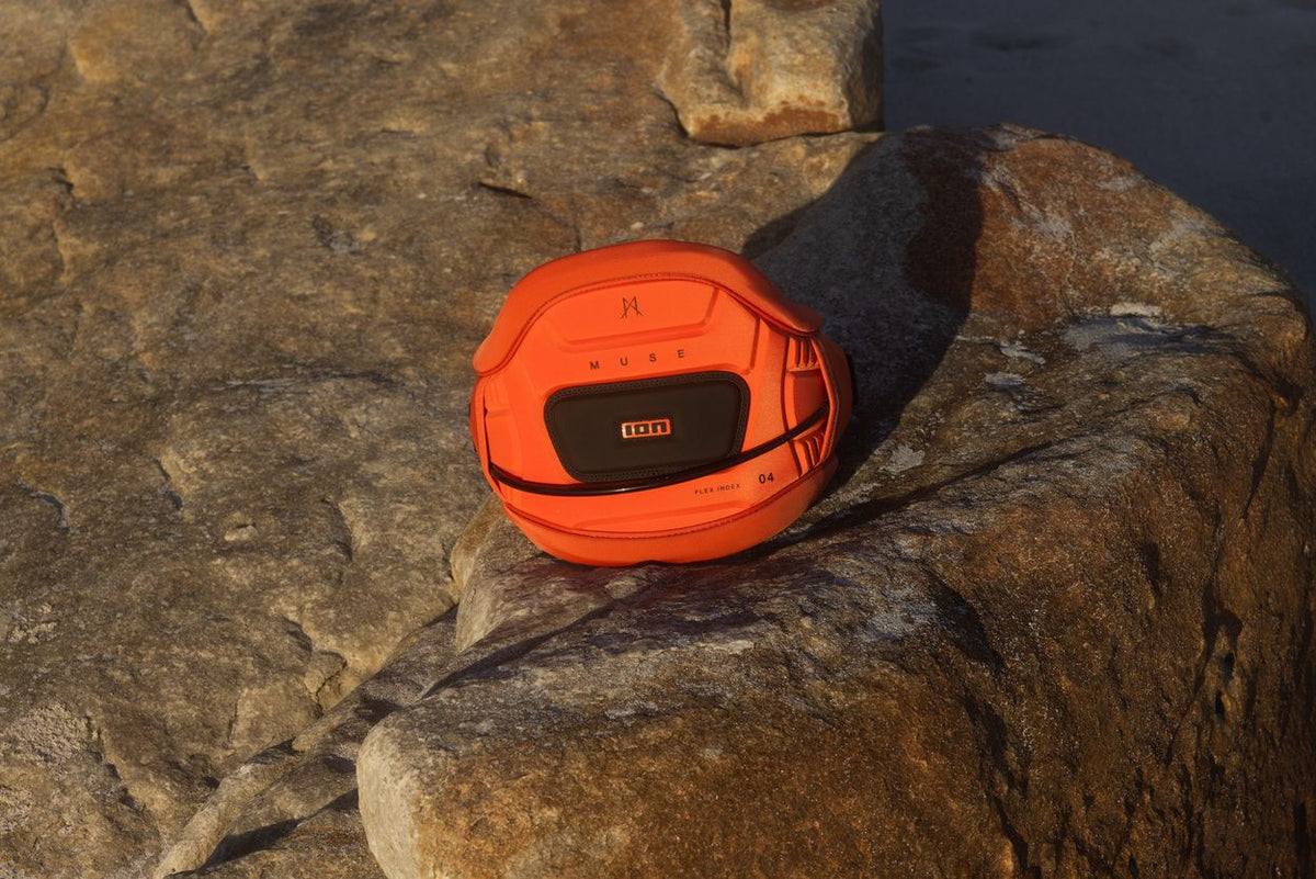 ION Muse Kite Trapez 2026 orange mit schwarzem Pad auf Felsen, Frontansicht