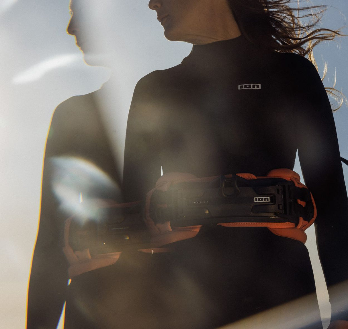 ION Muse Kite Trapez 2026 schwarz-orange, Kitesurfer trägt Trapez mit Bauchgurt, Frontansicht
