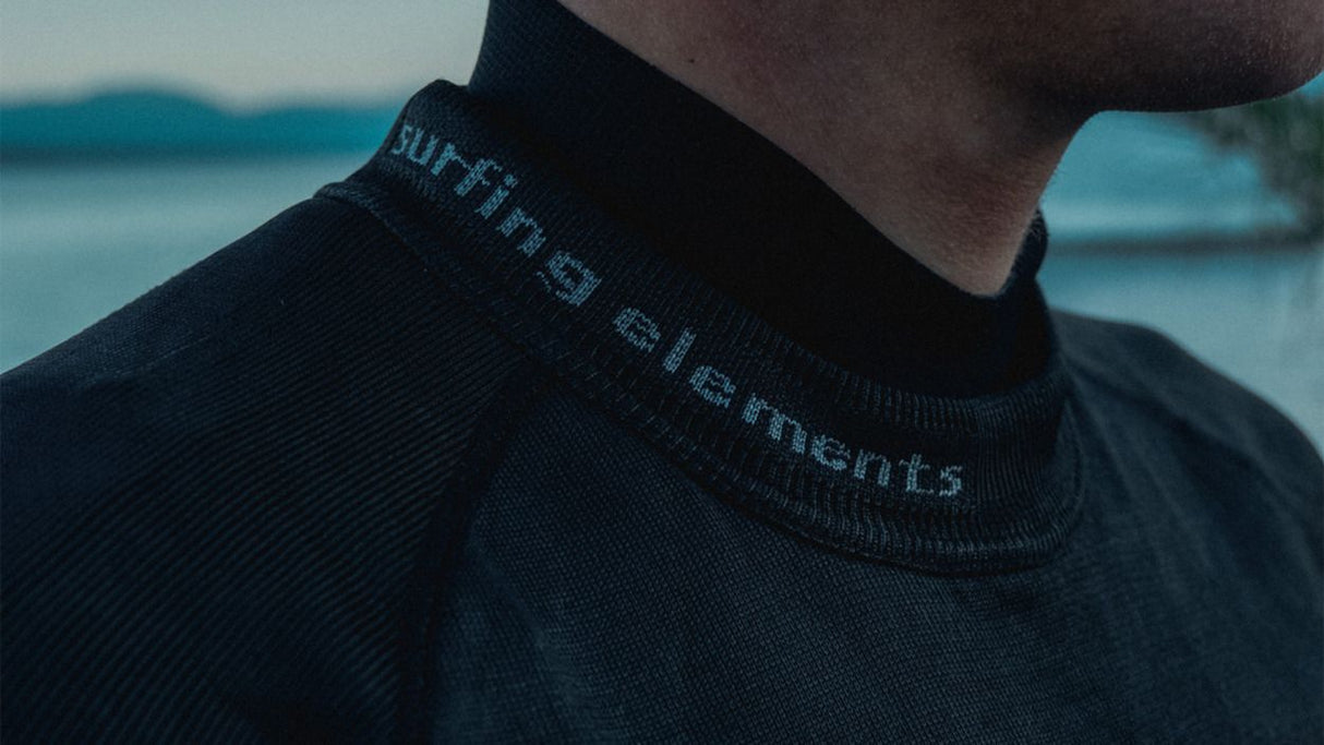 ION Rashguard LS Surf Shield SS2026 in Schwarz, Langarmshirt mit UV-Schutz, Detail Ausschnitt am Meer