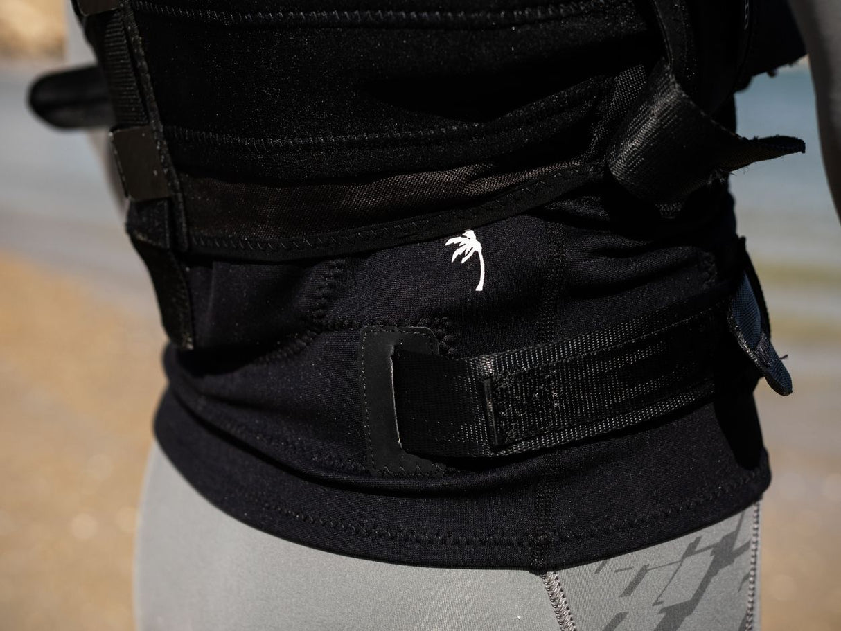 ION Rush Wing Vest 2026 schwarz, Neopren-Weste mit Verschlüssen, Detailaufnahme der Taille, Strandansicht