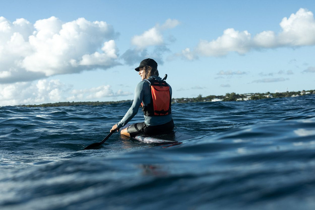 ION Explorer Bag 2026 rot, Wassersportler mit Rucksack im Meer sitzend, Frontalansicht