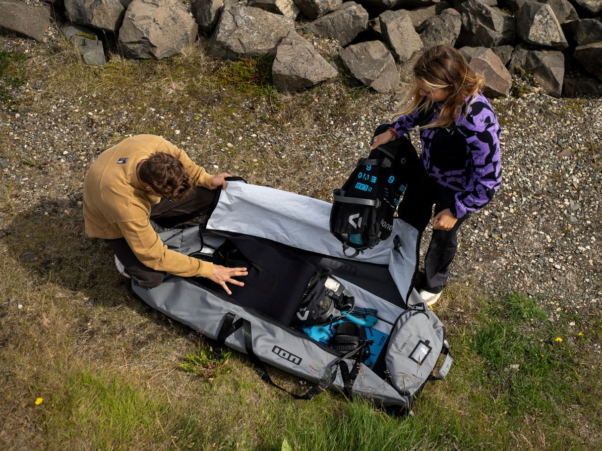 ION Kite Gearbag Core 2026 grau, geöffnet mit Kiteanlagen, Draufsicht, zwei Personen beim Packen