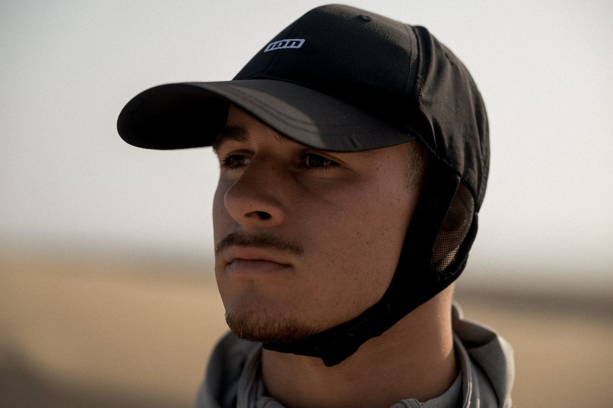 ION Surf Cap 2026 schwarz mit Neopren-Ohrenschutz, getragen von Mann im Freien, Frontalansicht