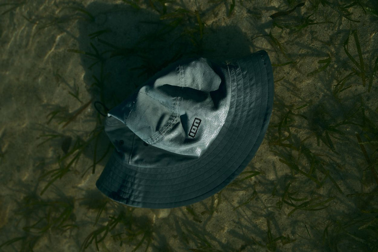 ION Bucket Surf Hat 2024 in Dunkelblau, Draufsicht auf strukturiertem Hintergrund, funktionaler Surfhut mit breiter Krempe