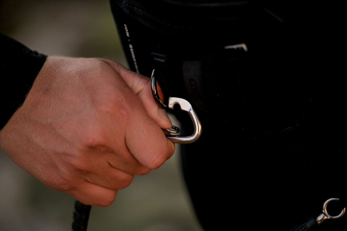 ION Wing Board Leash Core Hybrid mit Karabiner, schwarz, an Hand getragen, Detailansicht des Befestigungssystems