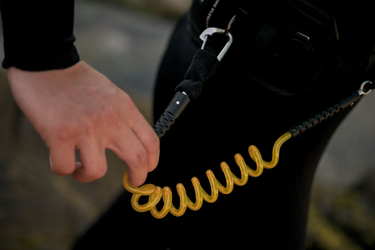 ION Wing Board Leash Core Hybrid mit goldenem Spiralkabel und Karabiner, an Hand getragen