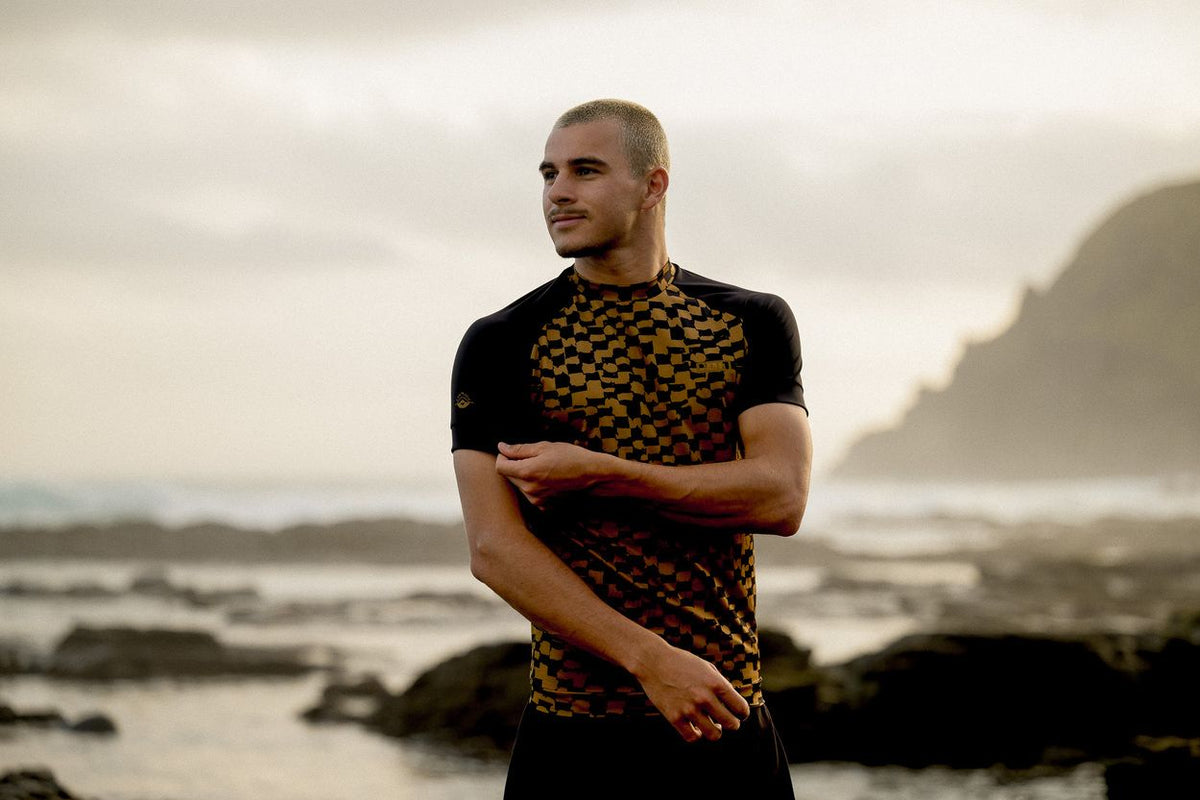 ION Maze 2026 schwarzes T-Shirt mit geometrischem Muster, Frontalansicht an Küste getragen
