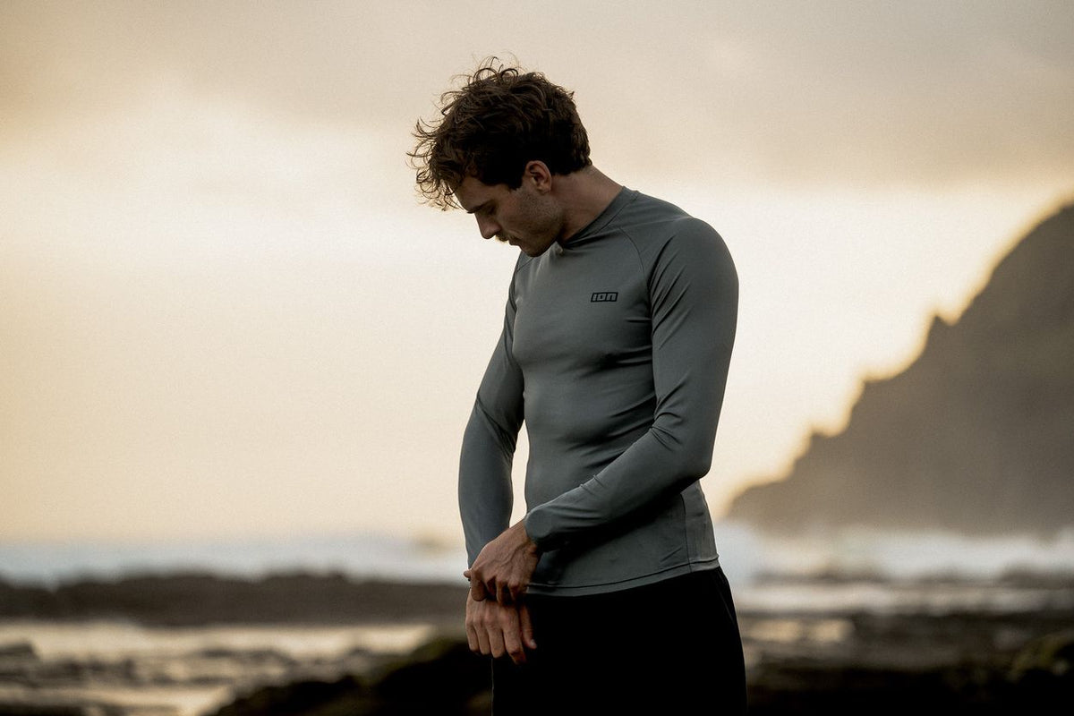 ION Rashguard LS 2026 grau, Langarm-Badeshirt aus Funktionsmaterial, getragen von Mann am Strand, Vorderansicht