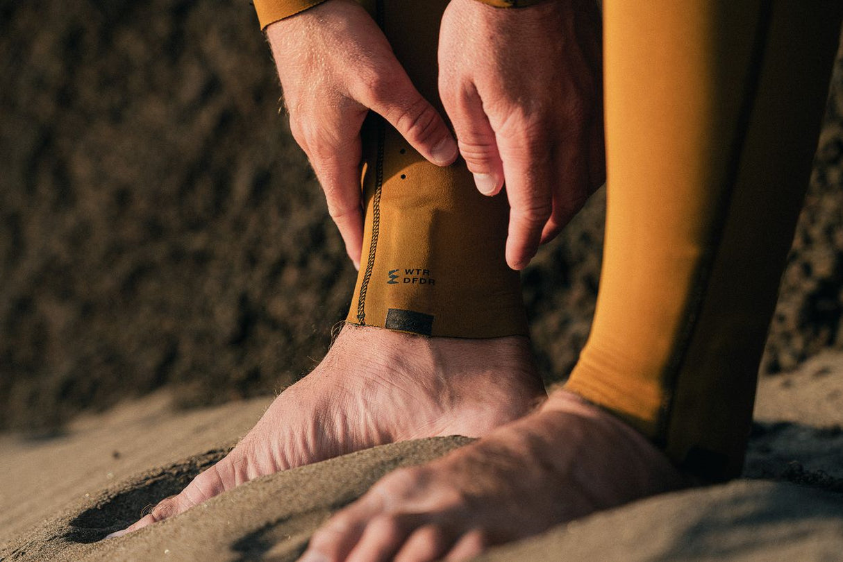 ION Seek Core 3/2 Front Zip Neoprenanzug in Goldgelb, Detail der Knöchelmanschette am Strand