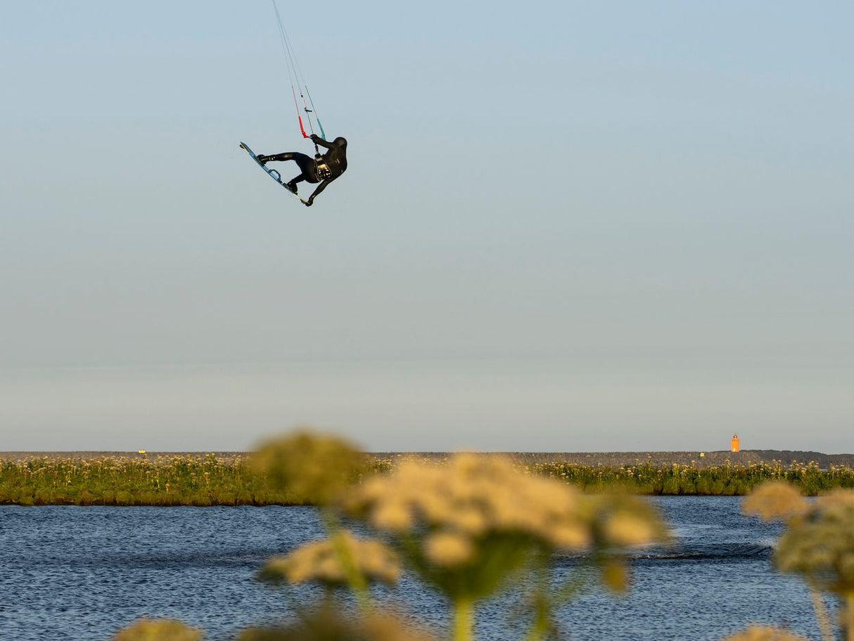 ION Riot Light 2026 Kite in Aktion über Wasser, Kitesurfer in der Luft, Seitenansicht