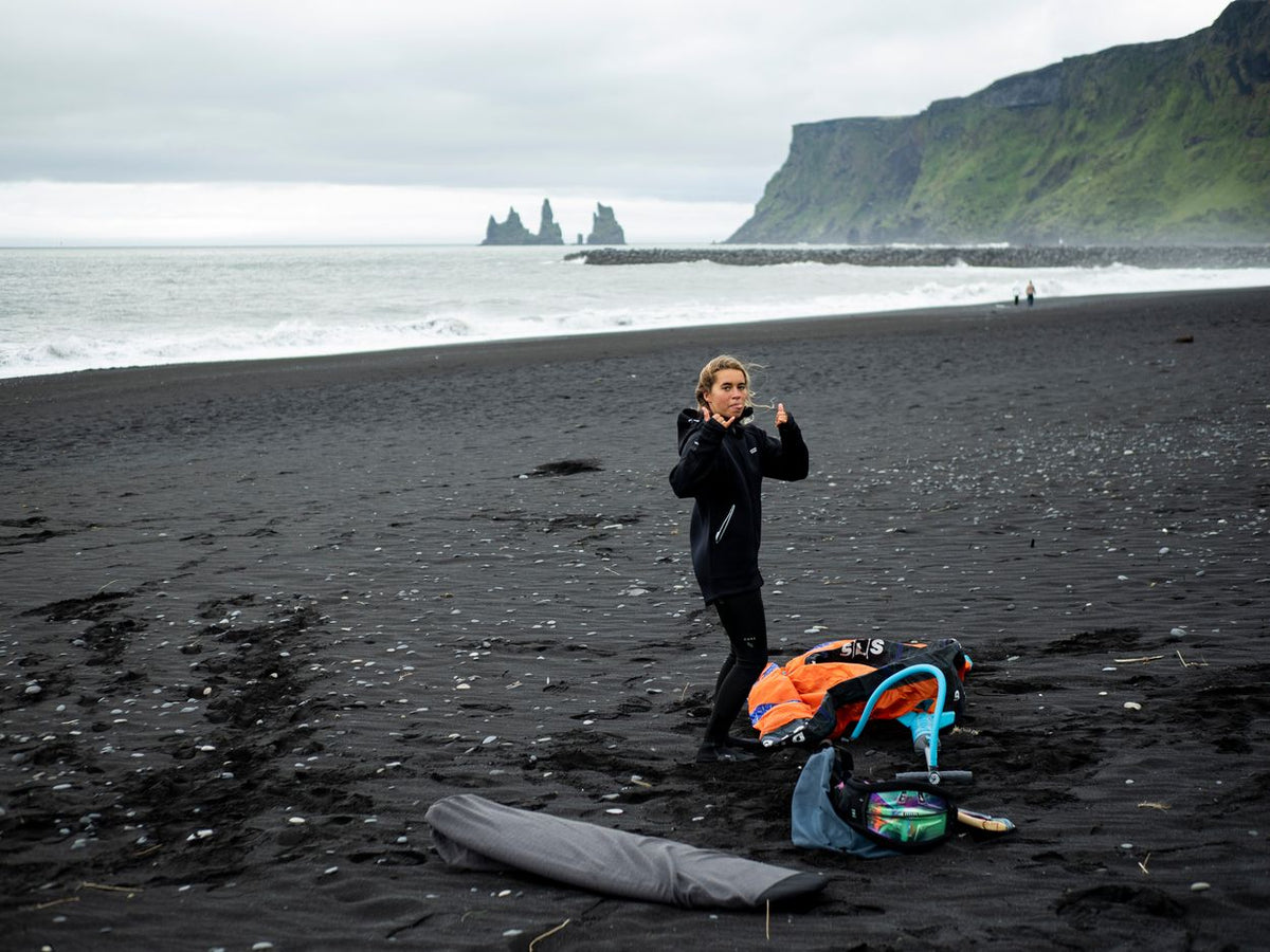 ION Neo Shelter Jacket 2024 in Schwarz, Neoprenjacke mit Reißverschluss, getragen am Strand, Frontansicht
