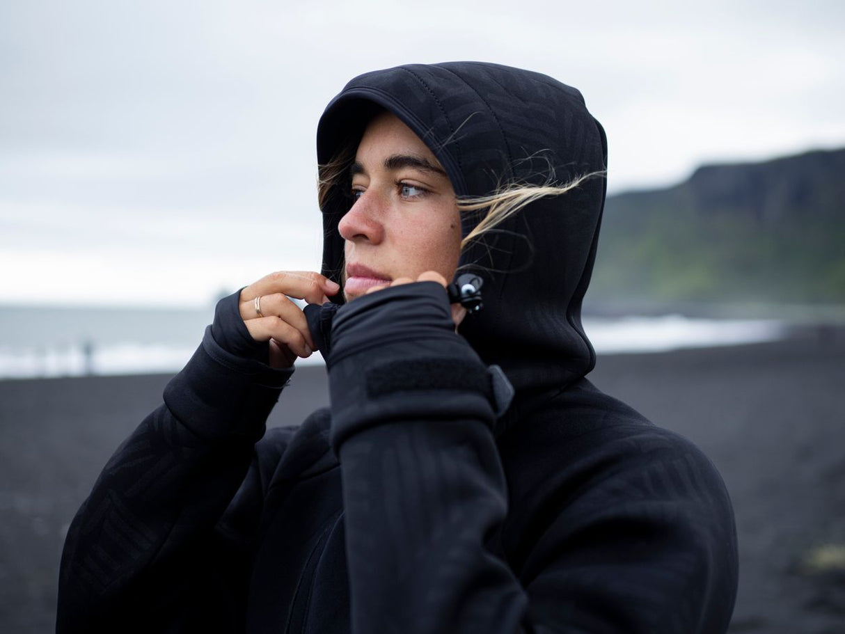 ION Neo Shelter Jacket 2024 schwarze Windjacke mit Kapuze, seitliches Porträt, Outdoor-Look am Strand