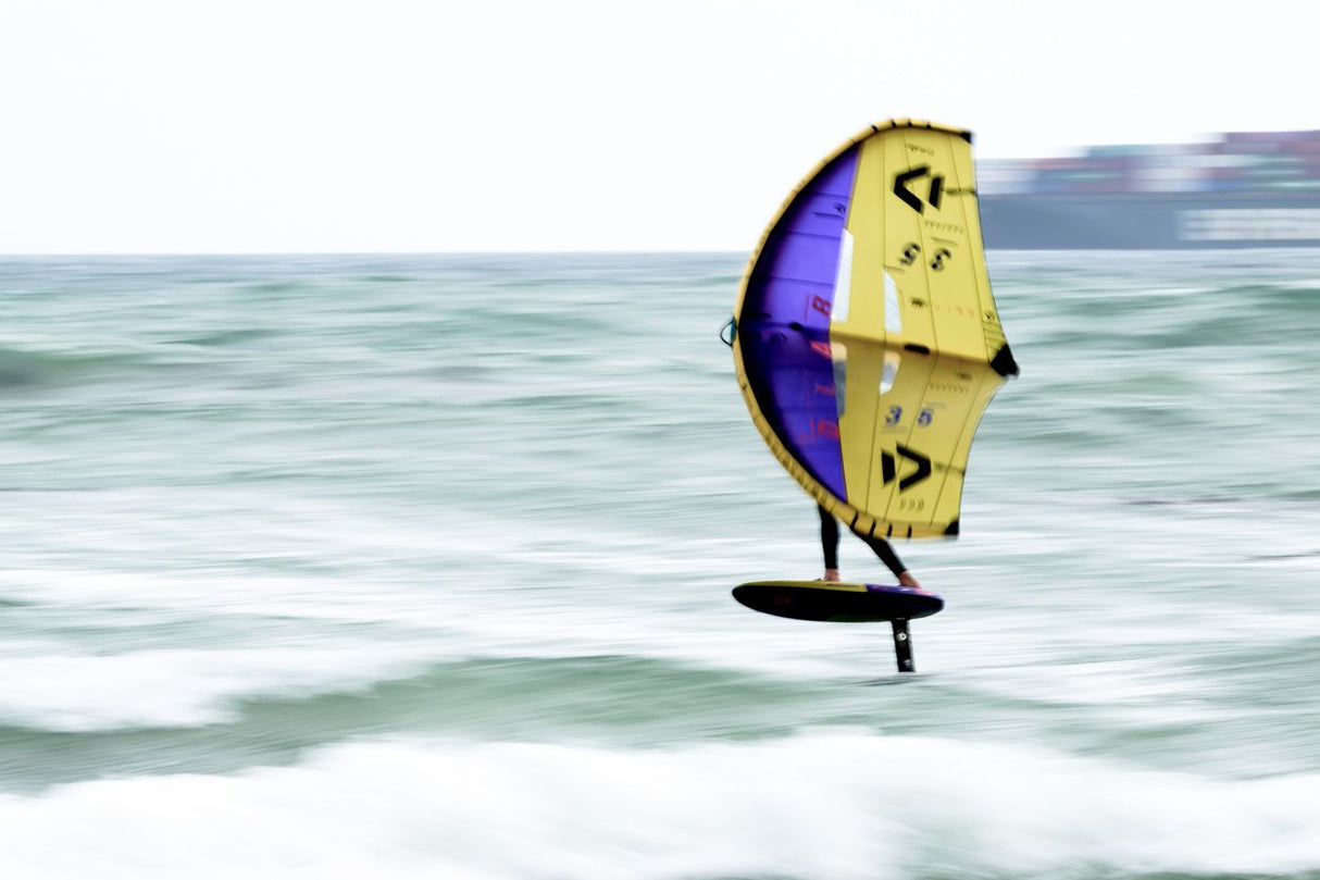 ION Hip Leash Wing/SUP Coiled 2024, gelb-violettes Flügelsegel mit Leash, Action-Perspektive am Meer