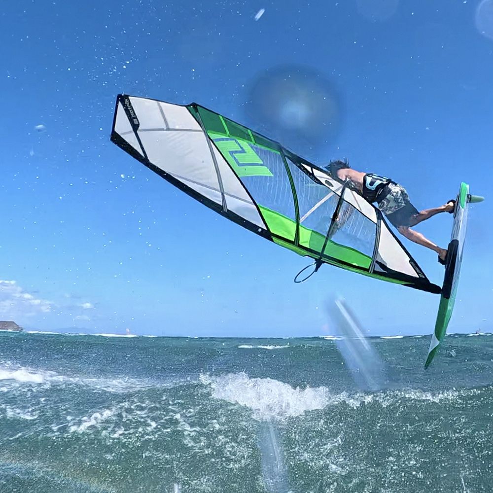 Patrik 4-Style Kite mit grünem und weißem Design, Kitesurfer in Aktion über Wellen, Frontalansicht