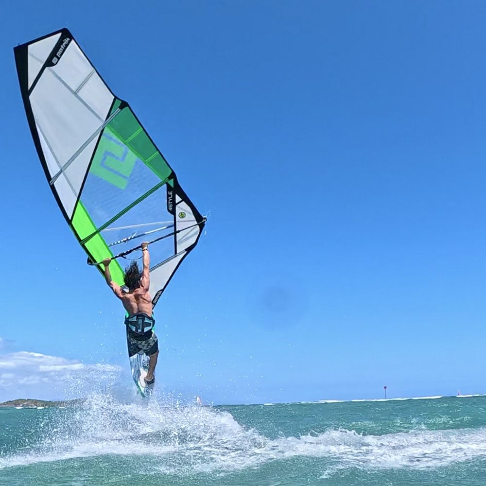 Patrik 4-Style Windsurfboard mit grünem und weißem Segel, Frontalansicht beim Wassersport im Meer