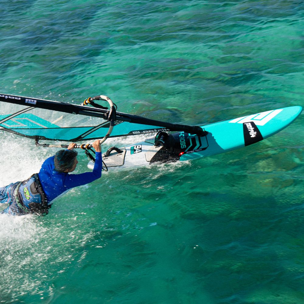 Patrik F-Cross Kiteboard in Türkis und Weiß mit schwarzem Gestänge, von oben im türkisfarbenen Wasser fotografiert