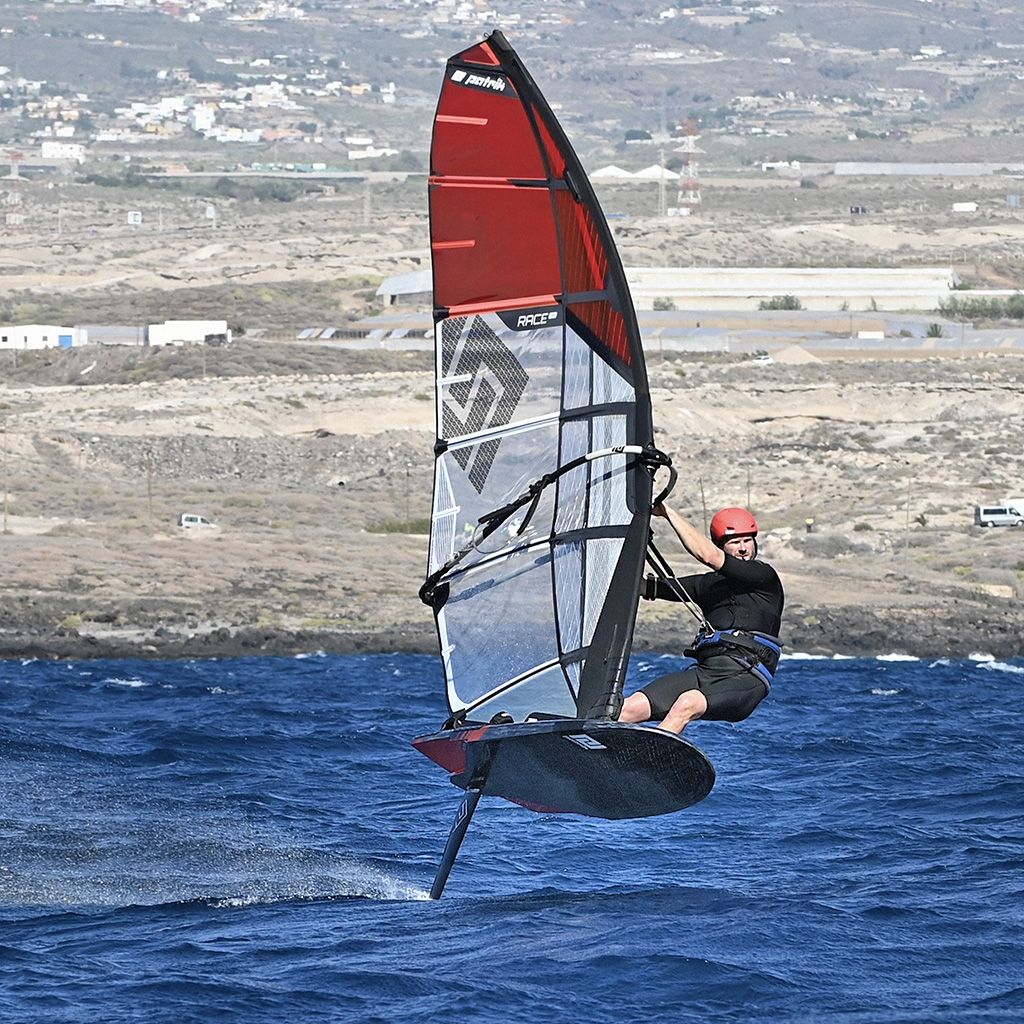 Patrik Foil Comp Gen3 Windsurf-Foil in Rot-Weiß, Sportler in Aktion auf dem Wasser, Seitenansicht
