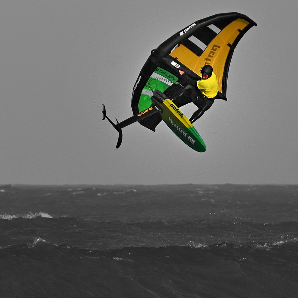 Patrik Wing V2 Volant Cross Kite in Gelb, Schwarz und Grün über dem Wasser, Seitenansicht