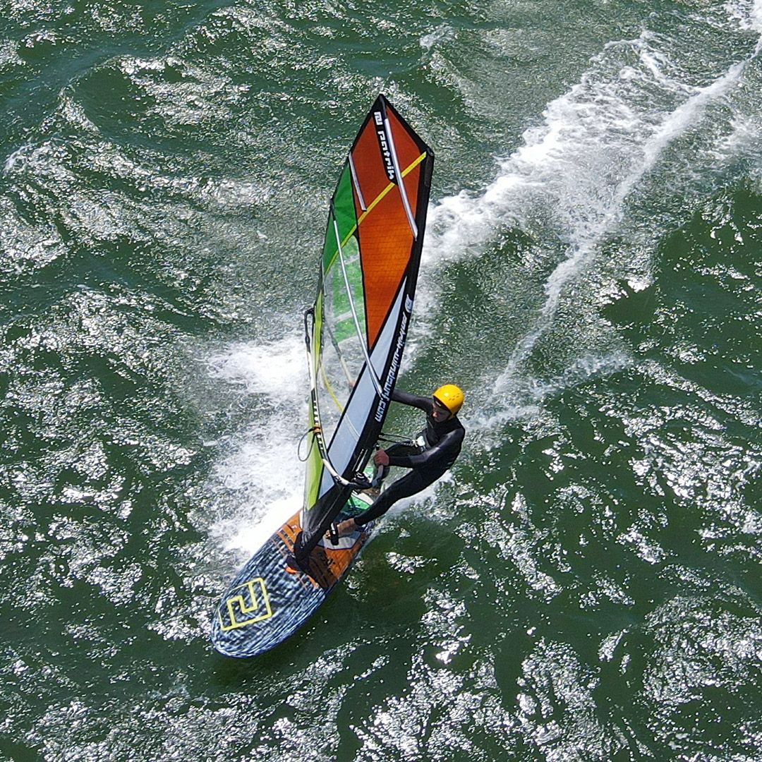 Patrik Micro-X GEN2 Waveboard in Grün, Orange und Schwarz, Draufsicht auf Wellen mit Windsurfer