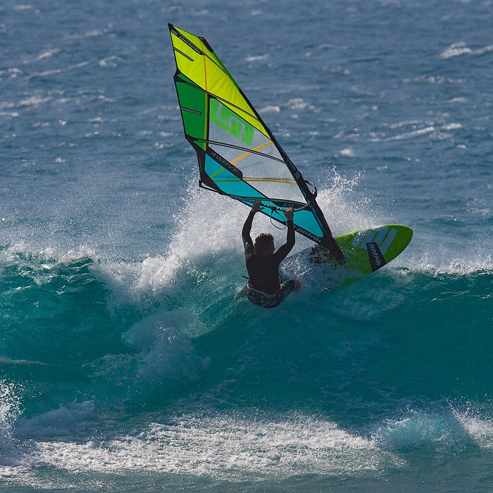 Patrik 4-Wave Windsurfboard in Gelb, Grün und Schwarz, von vorne in Aktion auf dem Wasser mit Windsurfer