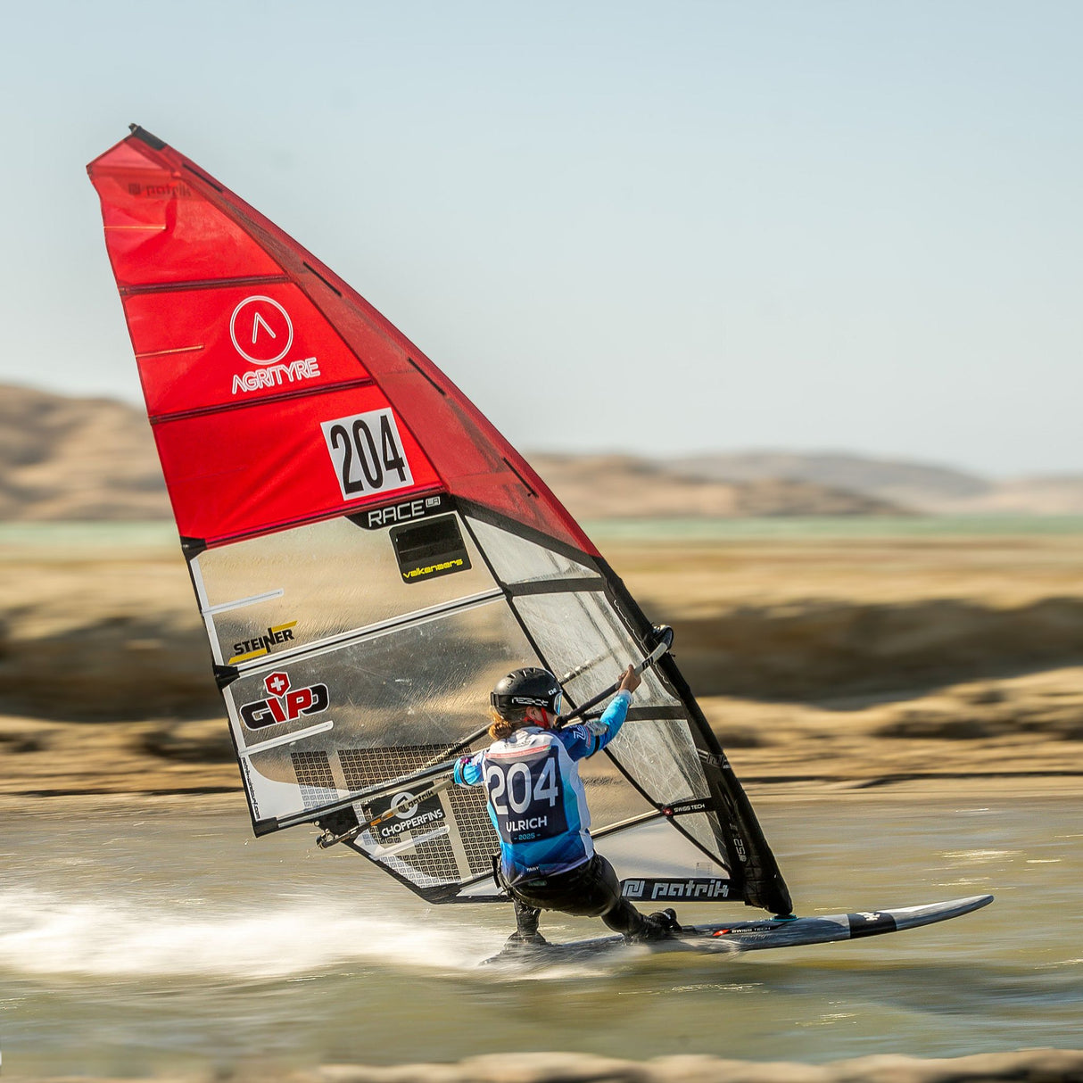 Patrik Speed Windsurfboard mit rotem Segel, Segelkennung 204, in Aktion auf dem Wasser, Frontalansicht