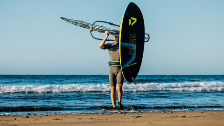 Duotone Skate D/LAB Kiteboard schwarz-gelb mit Finne, Frontalansicht am Strand mit Meer