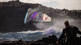 Duotone Super_Hero D/LAB 2027 Kite in Lila und Hellblau beim Kitesurfen über Wellen, Action-Perspektive