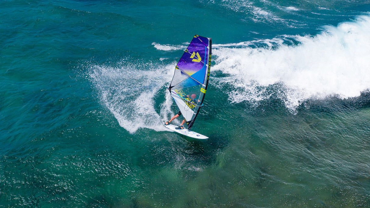 Duotone Super_Hero D/LAB 2027 Windsurf-Board in Violett und Grün auf Welle, Luftaufnahme
