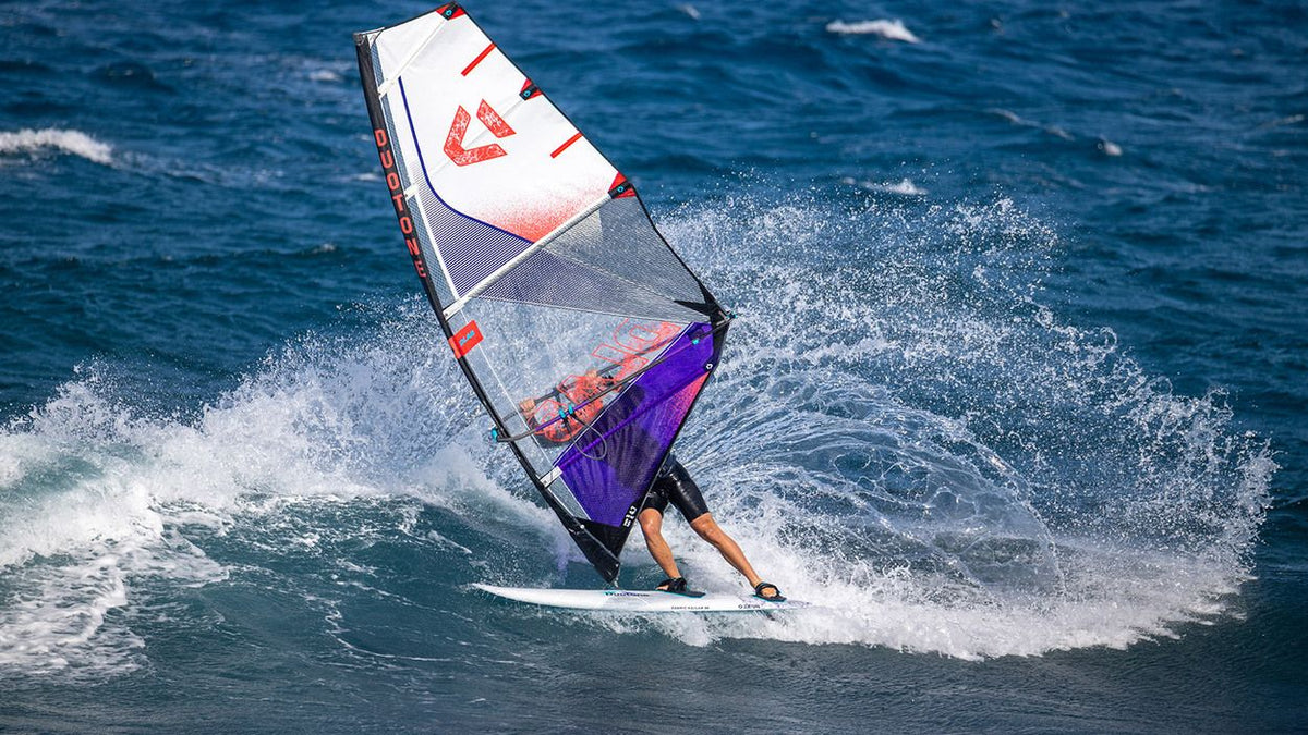 Duotone Super_Hero D/LAB 2027 Windsurfboard mit weiß-rotem Segel und violettem Board in Aktion auf dem Wasser