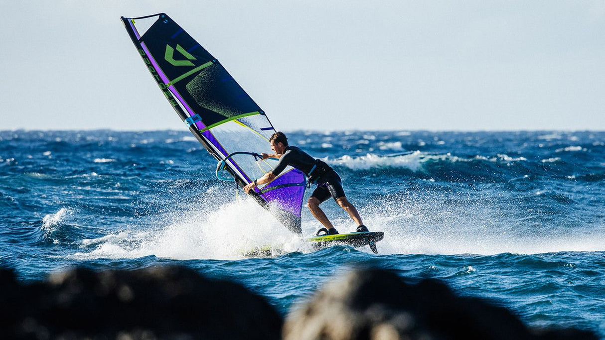 Duotone Sail Idol 2027 Windsurfegel in Blau und Grün, Athlet beim Windsurfen auf dem Meer in Aktion