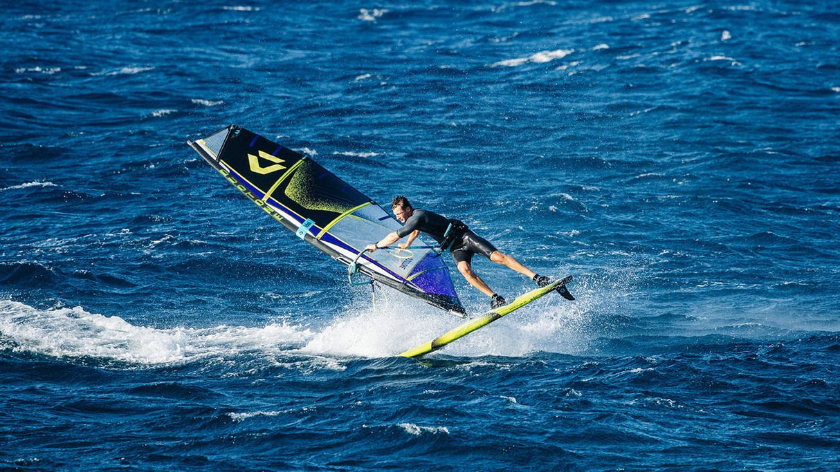 Duotone Sail Idol 2027 Kiteboard in Blau und Schwarz mit Segelausstattung in Aktion auf dem Wasser, seitliche Ansicht