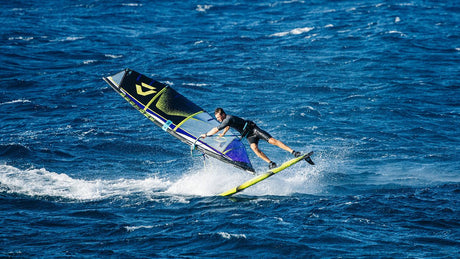 Duotone Sail Idol 2027 Kiteboard in Blau und Schwarz mit Segelausstattung in Aktion auf dem Wasser, seitliche Ansicht