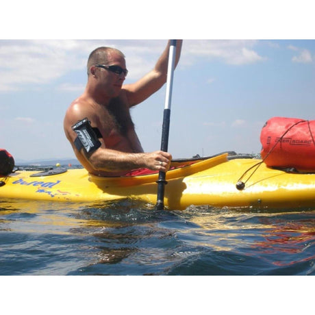 OverBoard Wasserdichte Armtasche PROSPORT in Schwarz, am Arm eines Mannes auf einem Kajak im Wasser befestigt