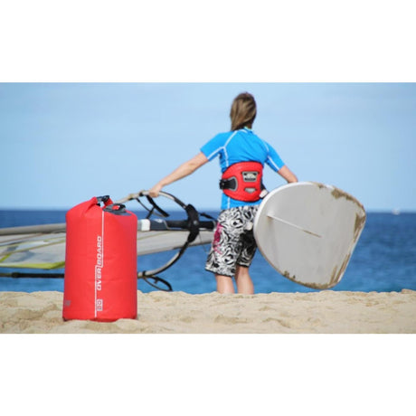 OverBoard wasserdichter Packsack 30 Liter rot, rollverschlossen, am Strand neben Wassersportler