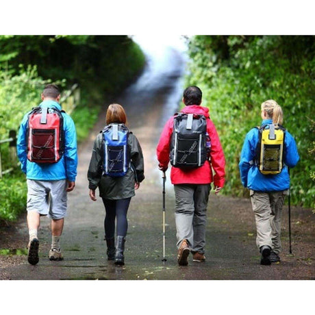 OverBoard wasserdichter Rucksack Pro 20L in Rot, Blau, Schwarz und Gelb, getragen von vier Wanderern auf einem Waldweg, Rückansicht