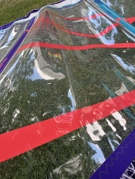 Duotone S-Pace 7.3 2026 Kiteboard mit roten und blauen Streifen, Draufsicht auf Wiese