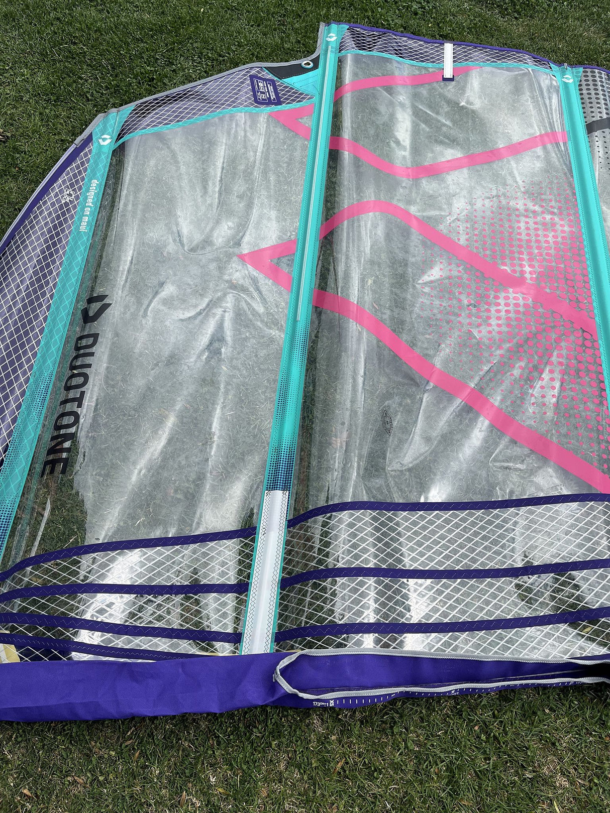 Duotone X Pace 5.8 2026 Kitesegel mit türkisem, pinkfarbenem und blauem Design, Draufsicht auf Gras