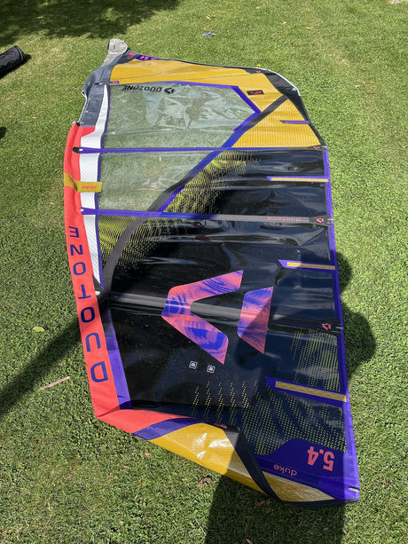 Duotone Duke 5.4 2026 Kiteboard in Gelb, Blau und Rot, aufgelegt auf Rasen, Draufsicht