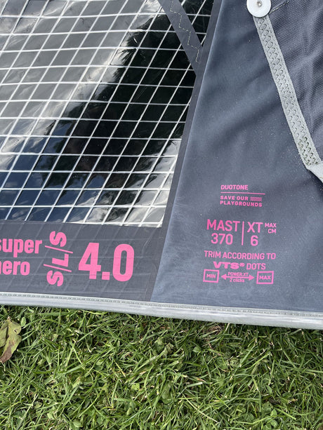 Duotone Super Hero SLS 4 2026 Kite mit Duotone-Branding in Grau und Pink, Detailansicht des Segels auf Rasen